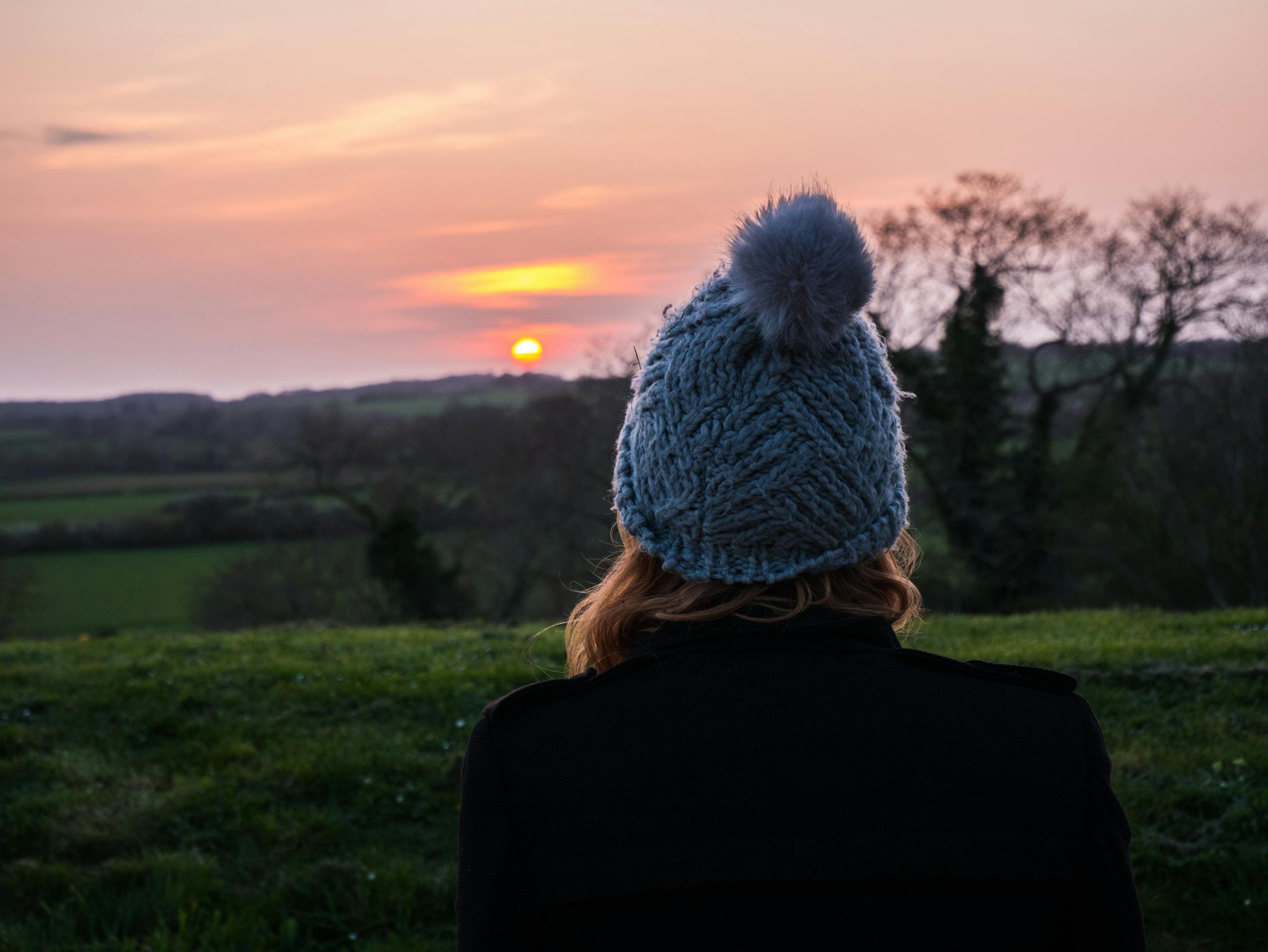 A person standing alone at the edge of a mountain overlook at sunrise — evoking quiet longing and the search for purpose.